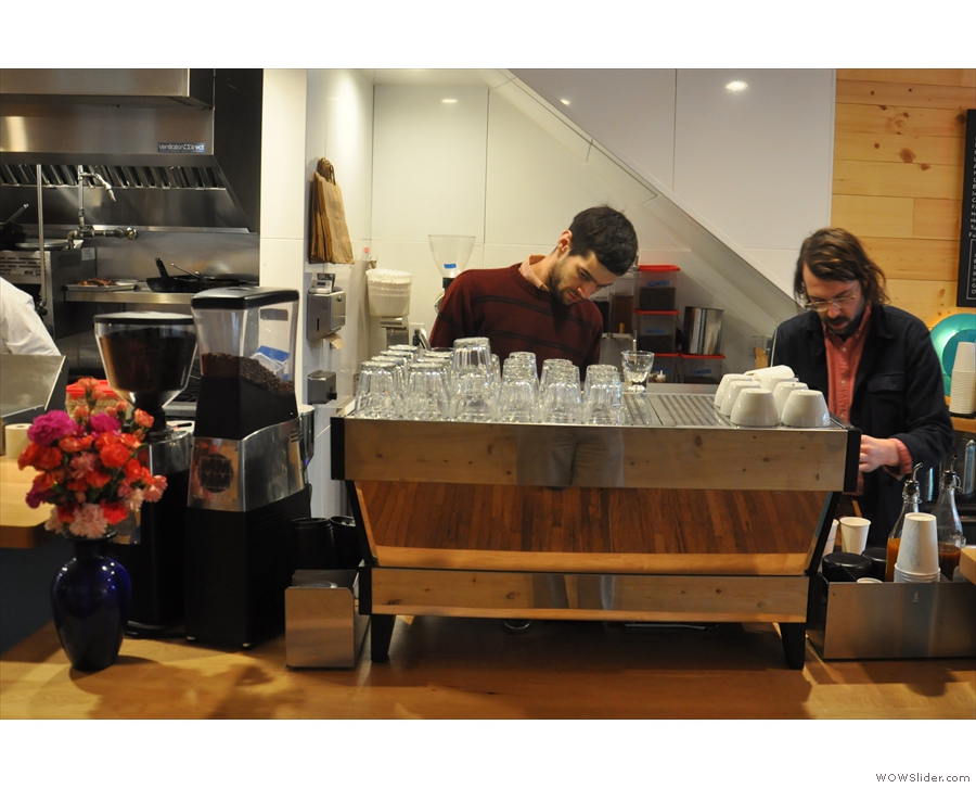 Baristas at work. There's a three-group La Marzocco with a pair of grinders...