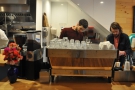 Baristas at work. There's a three-group La Marzocco with a pair of grinders...