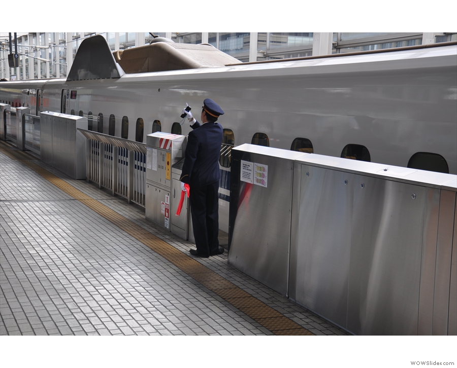 Japanese society's very personnel-intensive: a member of staff clears a train departure...
