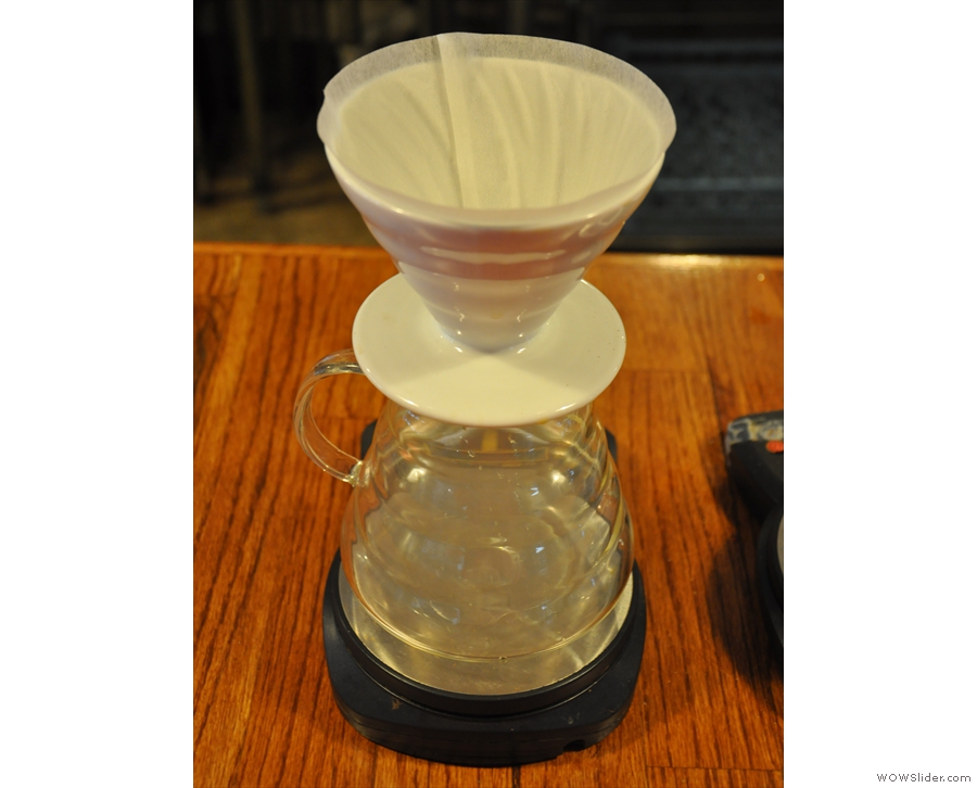 First, rinse the filter paper and then grind the coffee.