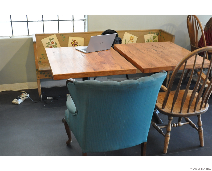 There's a smalerl wooden bench seat next to it with two smaller tables.