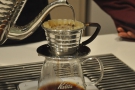 Each time, the barista uses short, controlled pours moving the kettle around the filter.