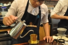 The first pour is to allow the coffee to bloom. I love the barista's look of concentration!