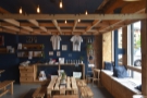 This is followed by a communal table in the centre of the space, retail shelves behind...
