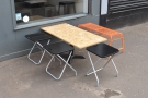 The broad pavement has plenty of space for this large chipboard table.