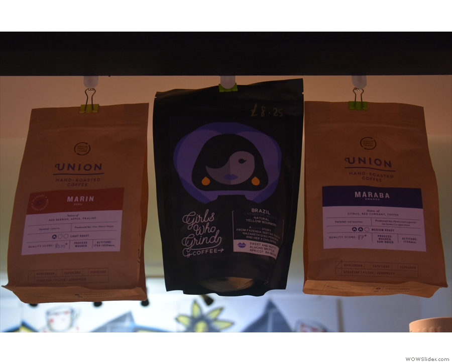 The coffee choices hang, in the form of bags of coffee, from a line above the counter.