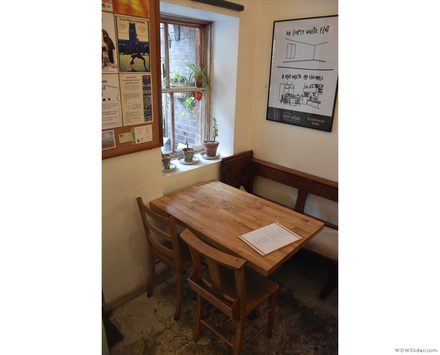 There are a pair of four-person tables to the left of the door: this one by the window...