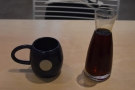 The coffee is served in a tall, narrow-necked carafe with a cup on the side.