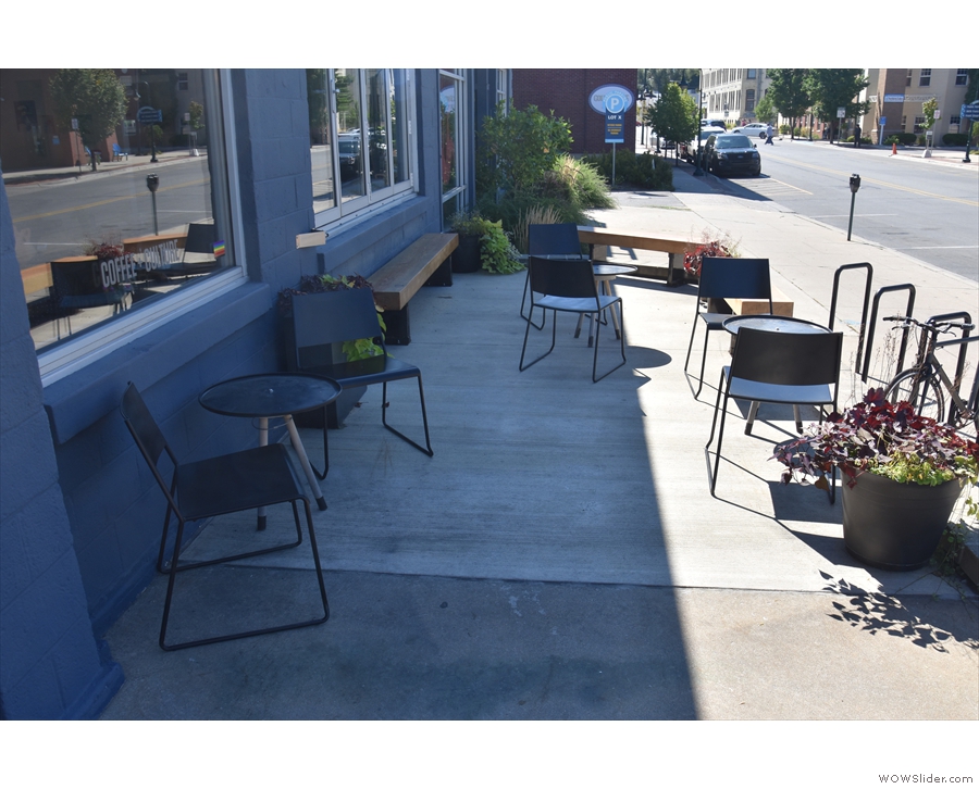 There's a raised outdoor seating area to the right, with three tables and two benches.