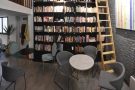 This is followed by a pair of round, three-person tables at the back by the bookshelves.