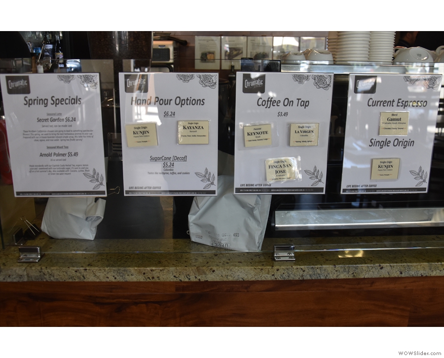 The extensive coffee choices are on the glass divider in front of the espresso machine.