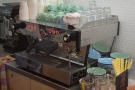 The espresso machine is at the far end of the counter, against the back wall.