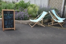 ... while on the other side of the path, there are three deck chairs and an A-board.