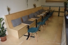 ... a long, box-bench seat with six two-person tables in front of it.