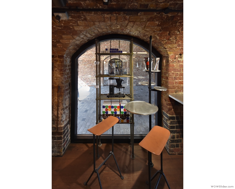 ... followed by a small, two-person table next to a smaller, arched window at the back.