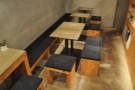 ... while beyond that are four more square two-person tables against another bench.