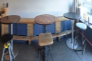 The tables, seen here head-on, with their mis-matching stools.