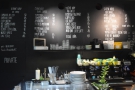 The menu, meanwhile, is on the wall behind the counter, the coffee arranged in columns...