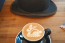 My flat white, with an obligatory hat in the background (sadly not a top hat!).