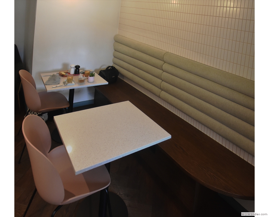 There's more seating along the right-hand wall, where a pair of two-person tables...