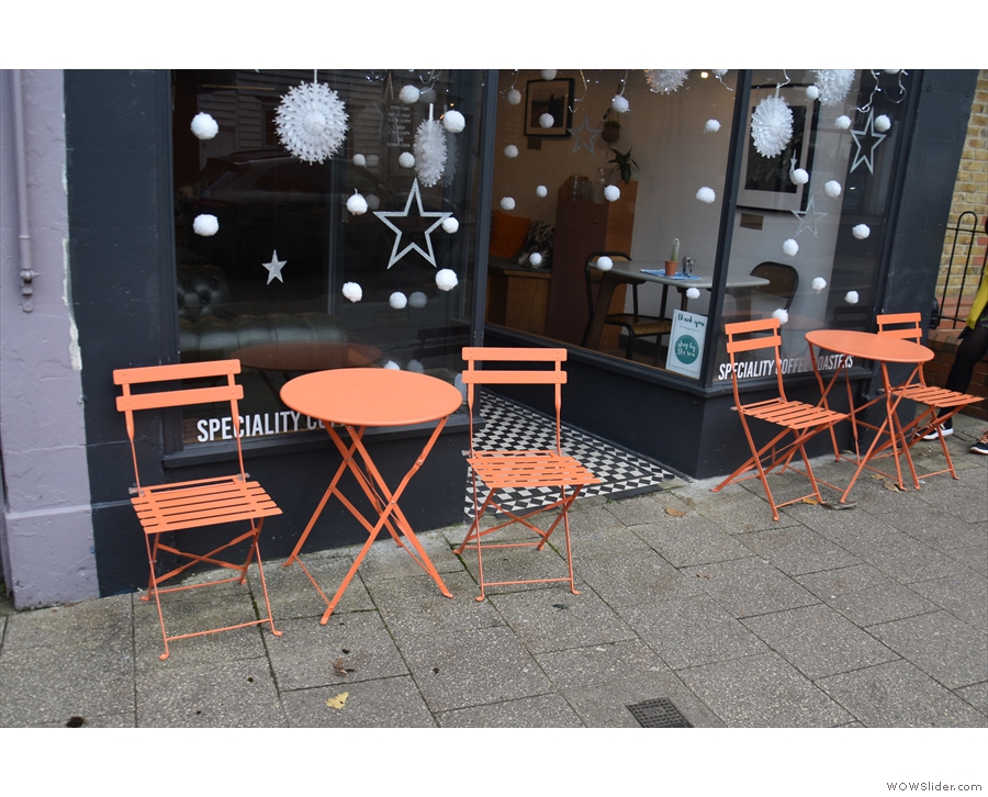 There's a pair of orange, two-person tables, one in front of each window.