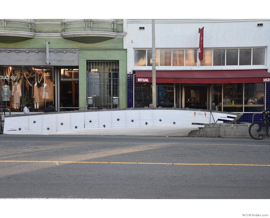 ... is a tall, single-storey white building with a red awning, home to Ritual Coffee Roasters.