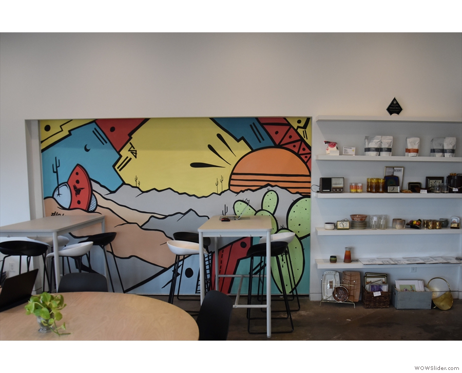 ... while beyond that are two, tall, four-person tables by a mural on the back wall.