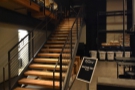 The stairs are at the back of the mezzanine, between it and the roastery.