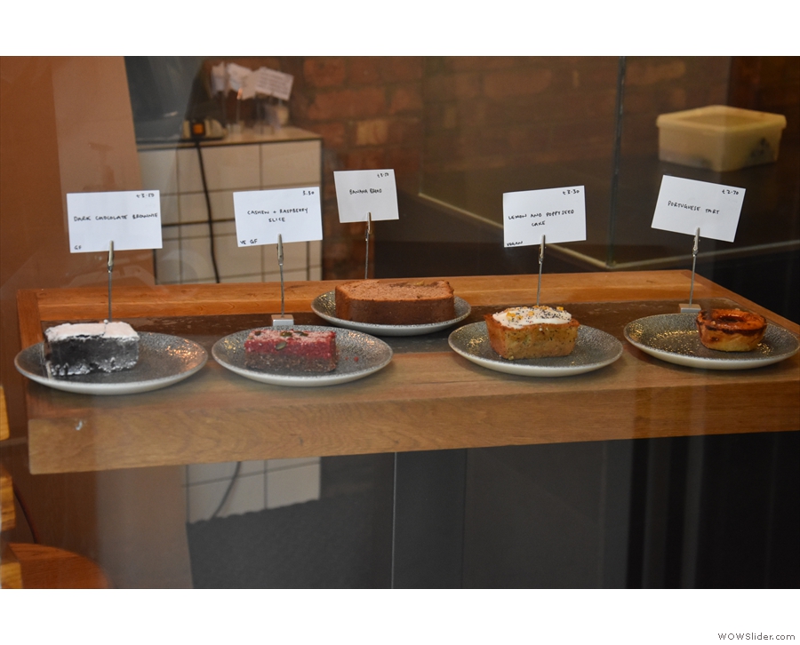 A cake display in the window to your left tempts you while waiting for a member of staff.