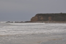 There is a solitary surfer (with a blue surf board) at the far end of the beach.