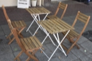 Two of the four two-person tables outside on the broad pavement.