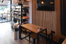 On the left, just after the chiller cabinet and retail shelves, is a four-person table...