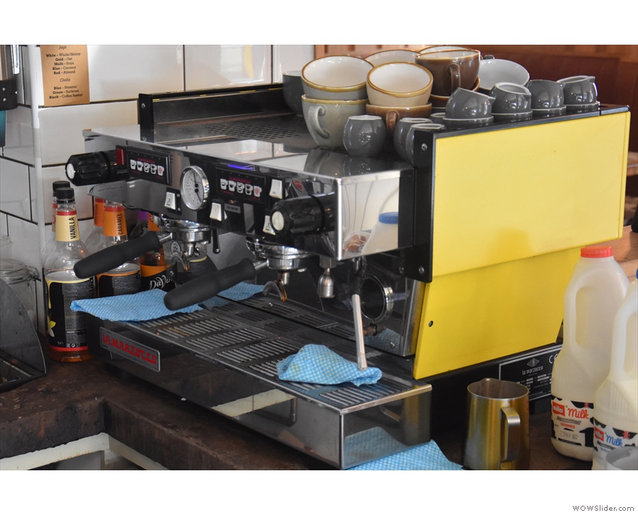 The coffee is made on the yellow La Marzocco Linea at the right-hand end of the counter.