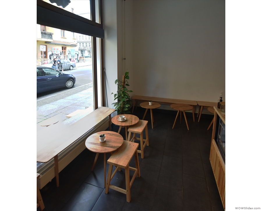 The seating starts to the left of the door with a window-bench and two tables...