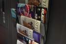 Outside in the corridor is an old-school magazine rack. The corridor continues...
