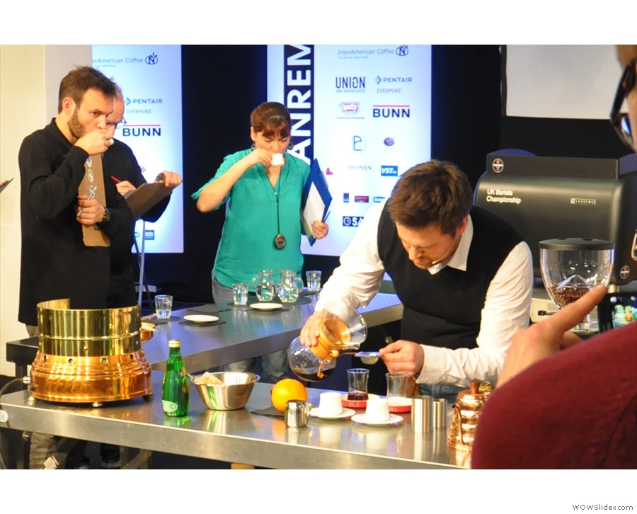 While the judges sample the coffee. Vadym pours the filtered coffee through a tea-strainer.