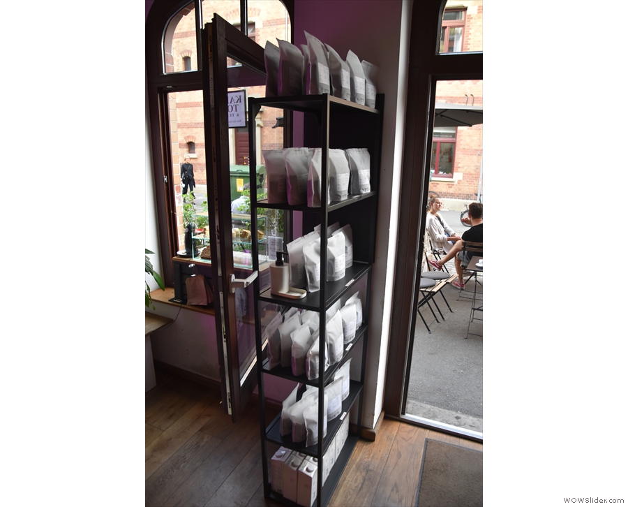 To the right of the door, more racks of shelves hold retail bags of coffee, as do the...