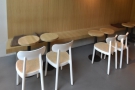 A low bench runs around the wall, lined with small round tables, each with a chair.