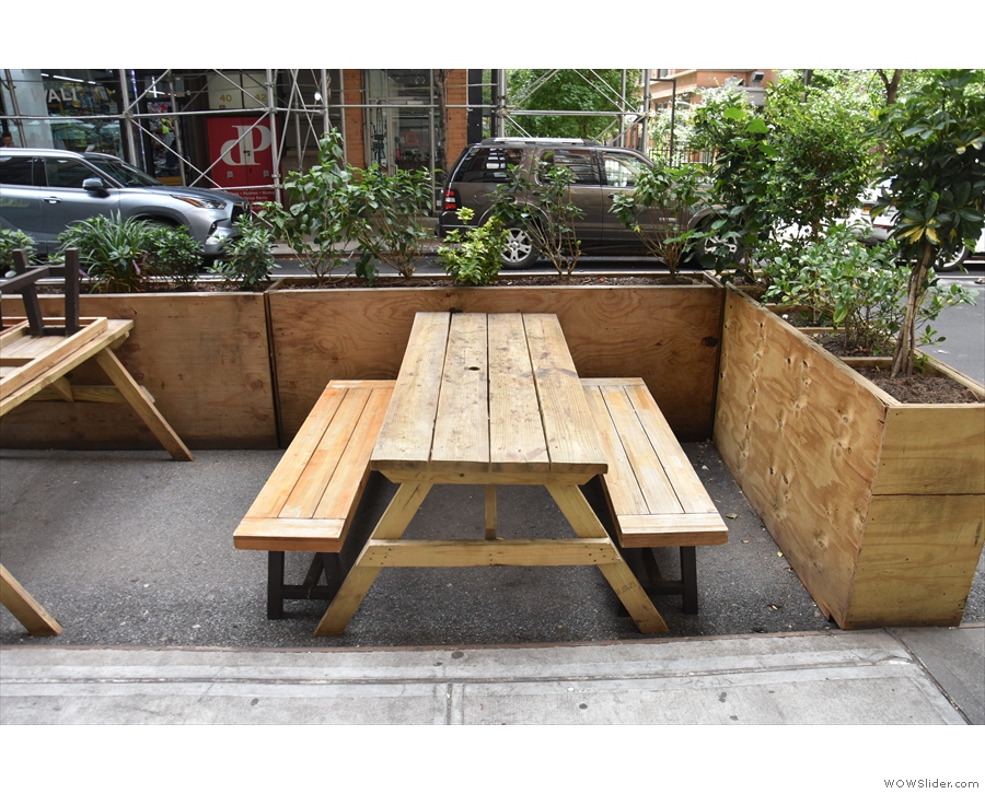 ... by waist-high wooden planters, which protect an outdoor seating terrace.