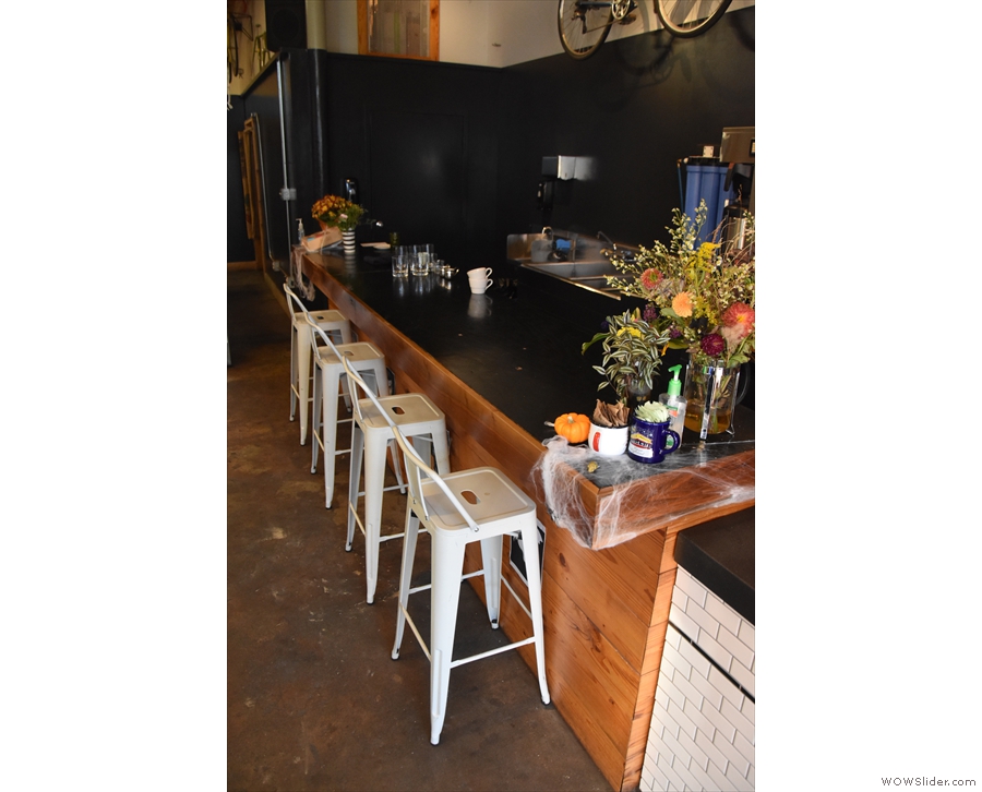 On the right, past the espresso machine, four chairs stand at an extension to the counter.