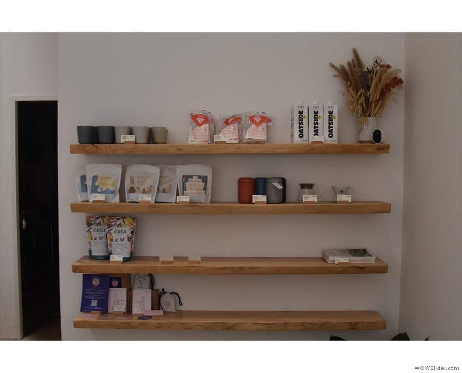 The back wall itself is home to these retail shelves, where you'll find bags of coffee for sale.