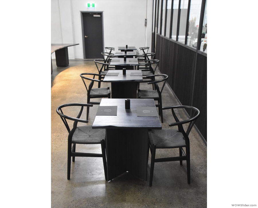 These tables have chairs on either side, facing the counter (right) or roastery (left).
