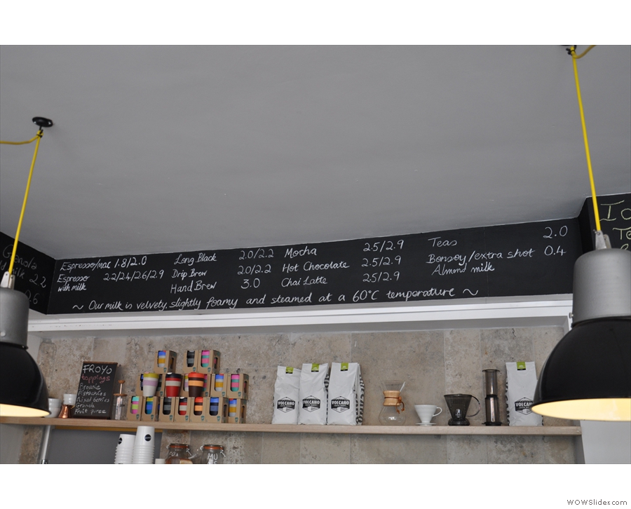 The coffee menu is written on a board above the counter.