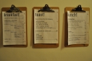 The food menus (all-day breakfast, lunch and toast) hang on the wall.