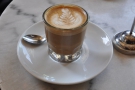 My flat white, beautifully presented in a glass.