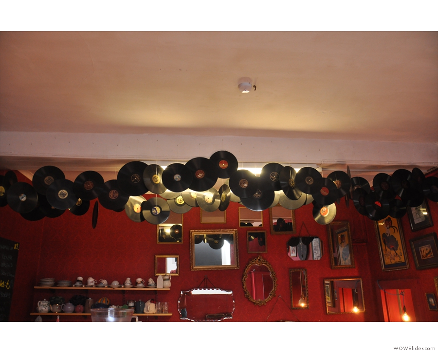 Old vinyl records hang from the ceiling in front of the wall, itself adorned with mirrors.