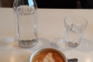 My flat white, complete with complimentary bottle of water: the joys of table service.