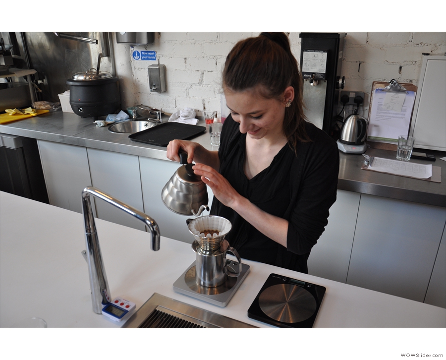 After putting the coffee into the Kalita Wave filter, she adds hot water.