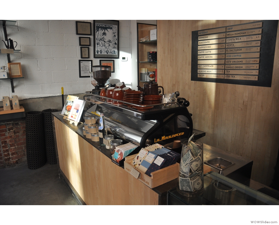 The counter is opposite the door, the espresso machine at the left-hand end.