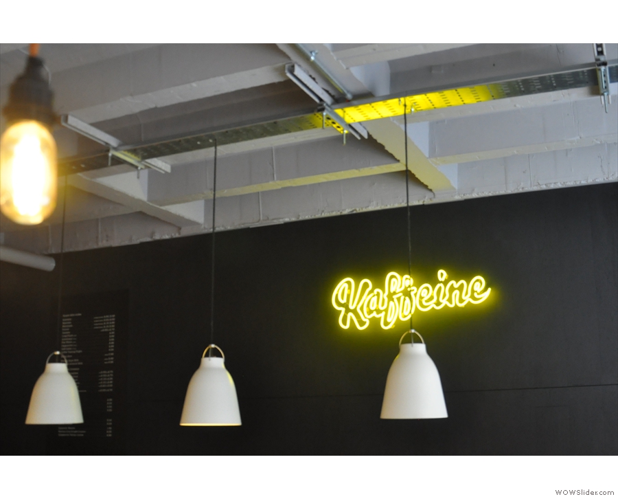 The (very prominent) Kaffeine logo in yellow neon is to the right, behind the counter.